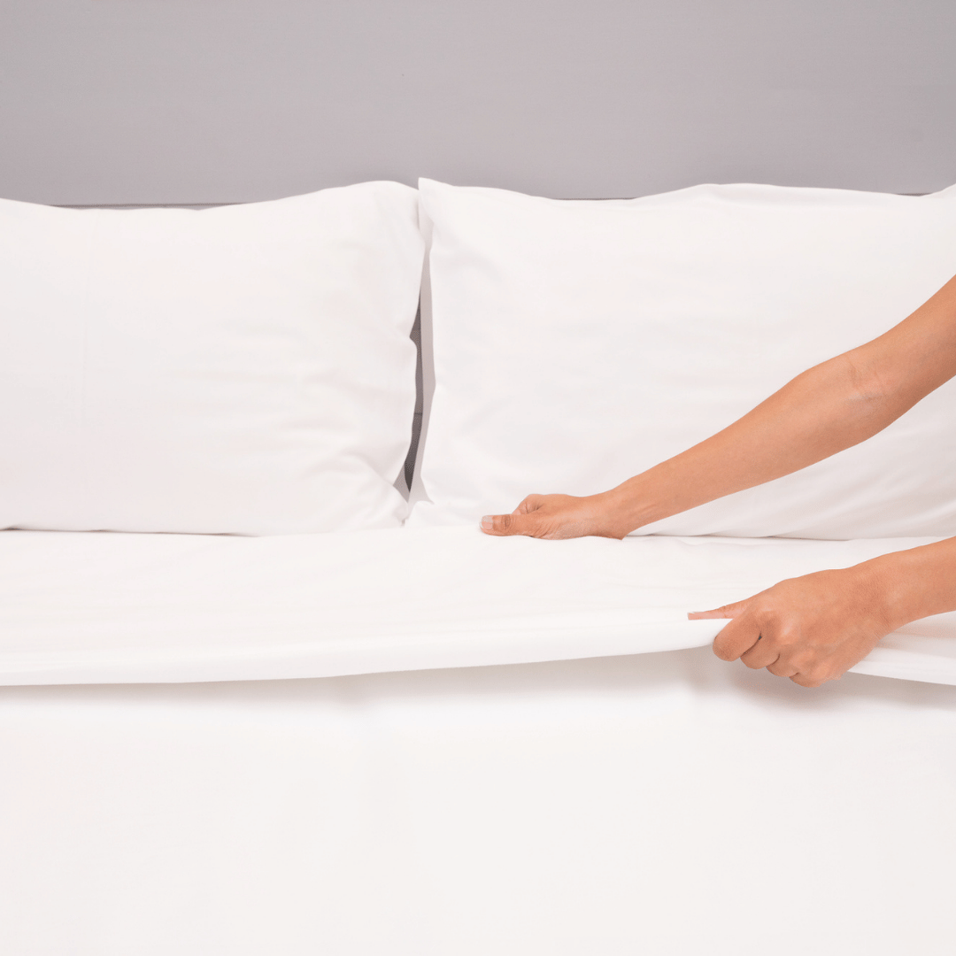 Mise en place d’un drap plat blanc sur un lit Image