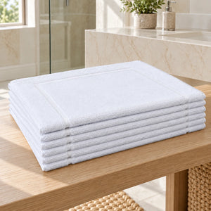 Lot de 6 tapis de bain blancs Élégance 800 g/m² pliés dans une salle de bain