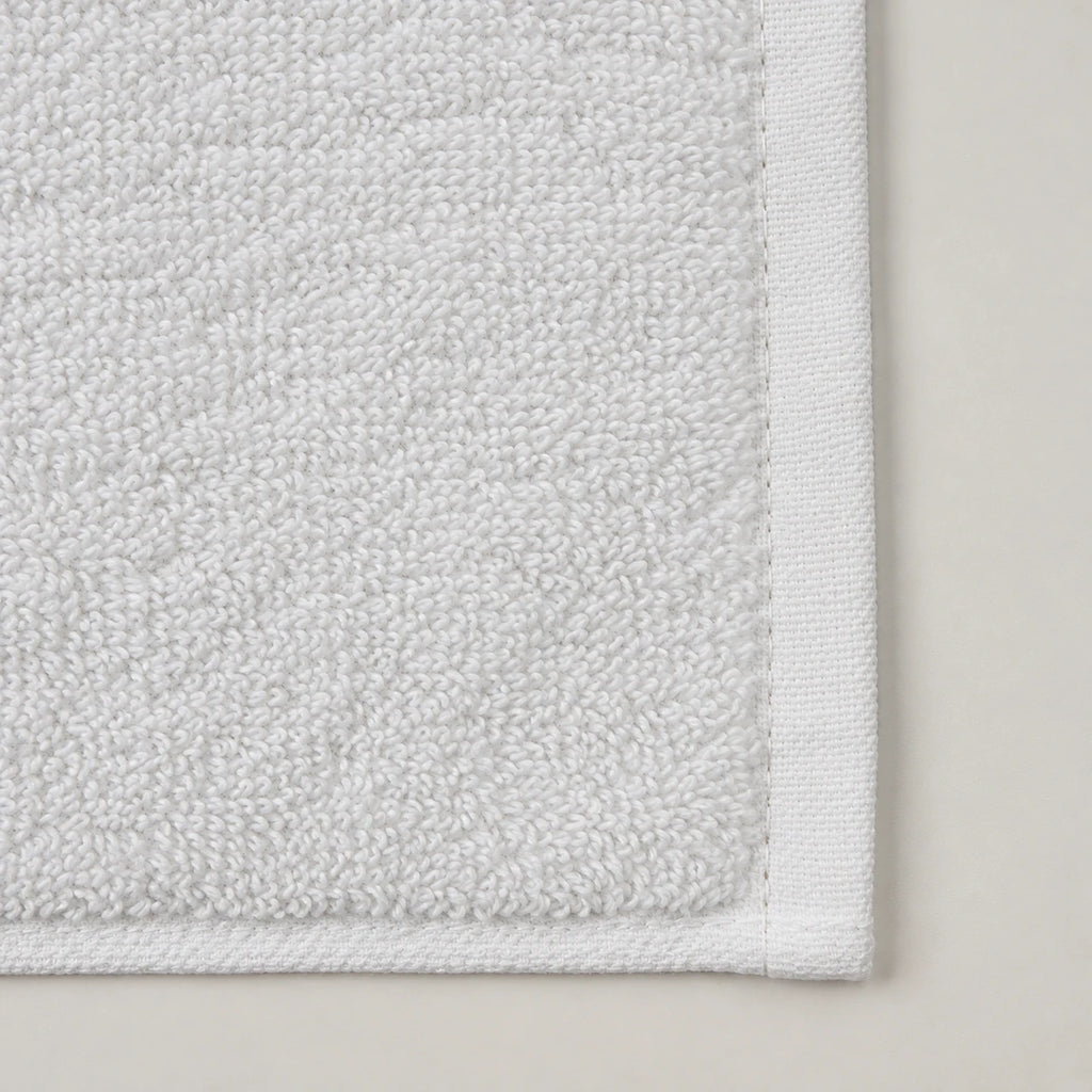 Détail de l’éponge double boucle et de la bordure tissée du tapis de douche