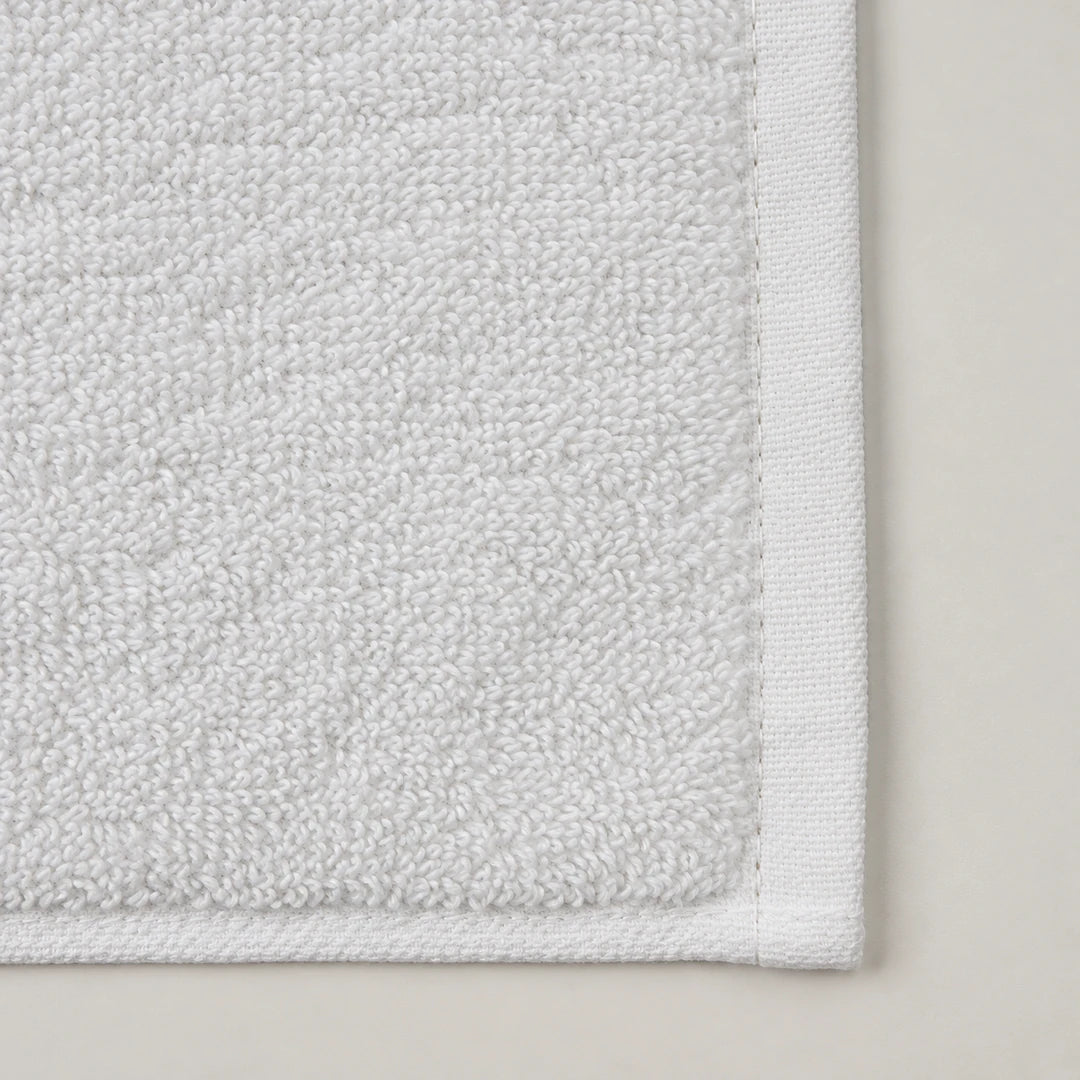 Détail de l’éponge double boucle et de la bordure tissée du tapis de douche